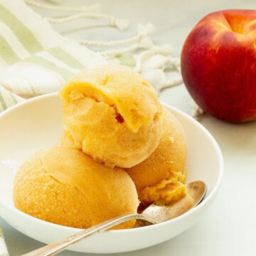 A white bowl with three scoops of peach sorbet.