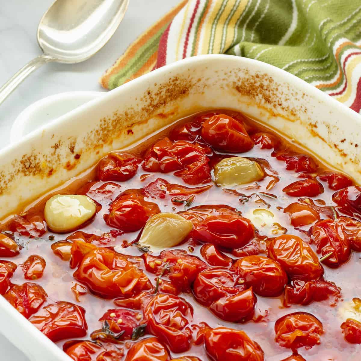 A white casserole dish with slow roasted grape tomatoes and garlic