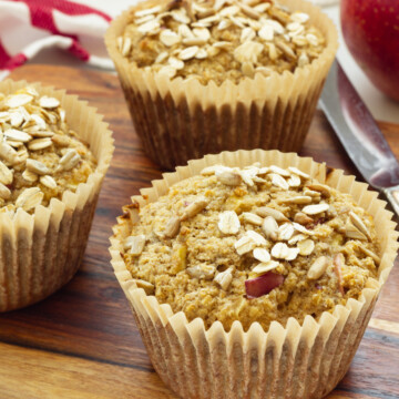 Three oat bran muffins in paper wrappers. A red and white striped napkin is in the background.