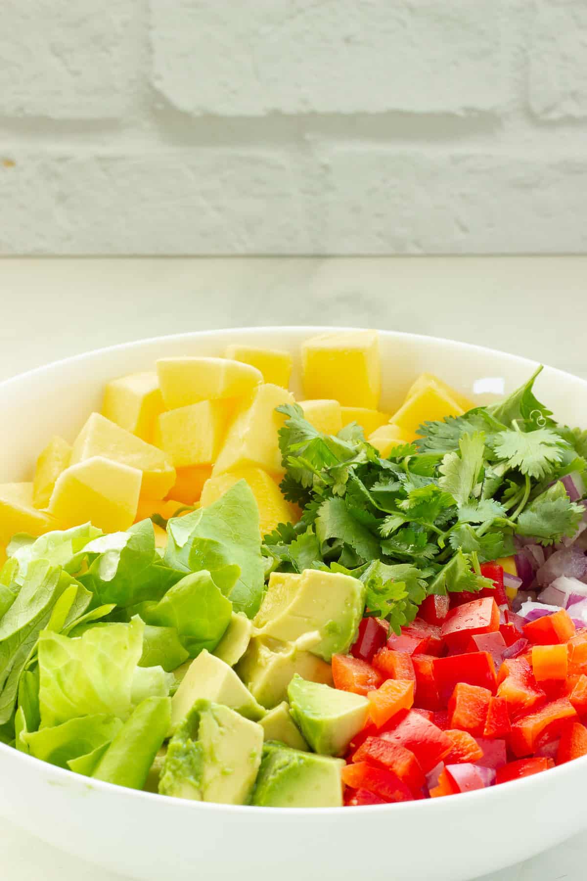 A mixing bowl with prepped ingredients for mango avocado salad