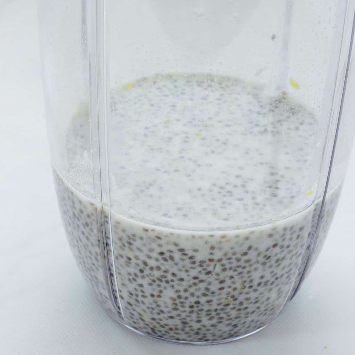 A bullet blender jar with chia seeds and almond milk.