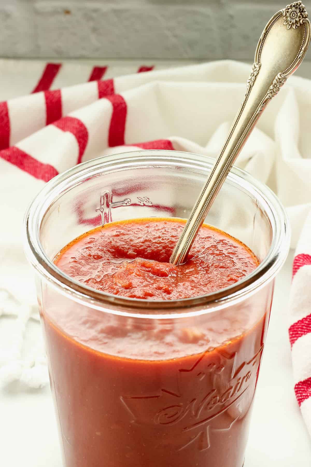 A jar of easy pasta sauce with a spoon in it.