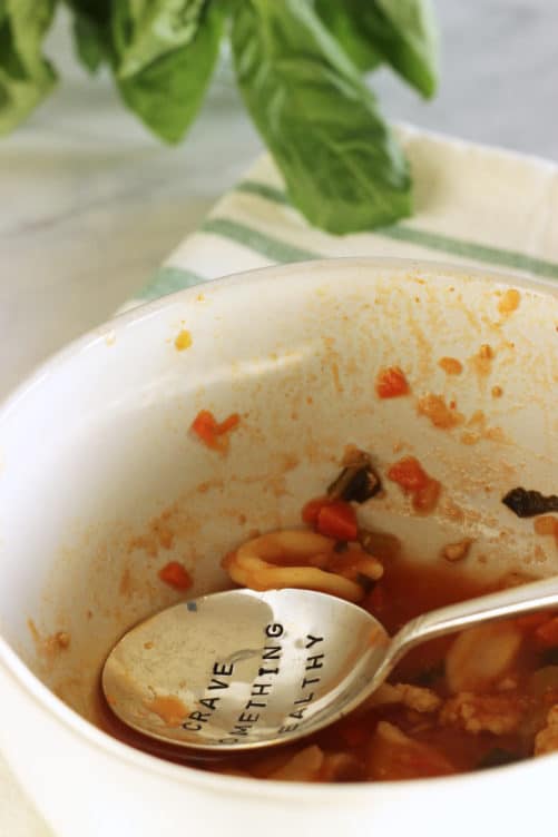 A photo of a mostly empty bowl of ground turkey soup. A spoon that says Crave Something Healthy sits in the bowl.