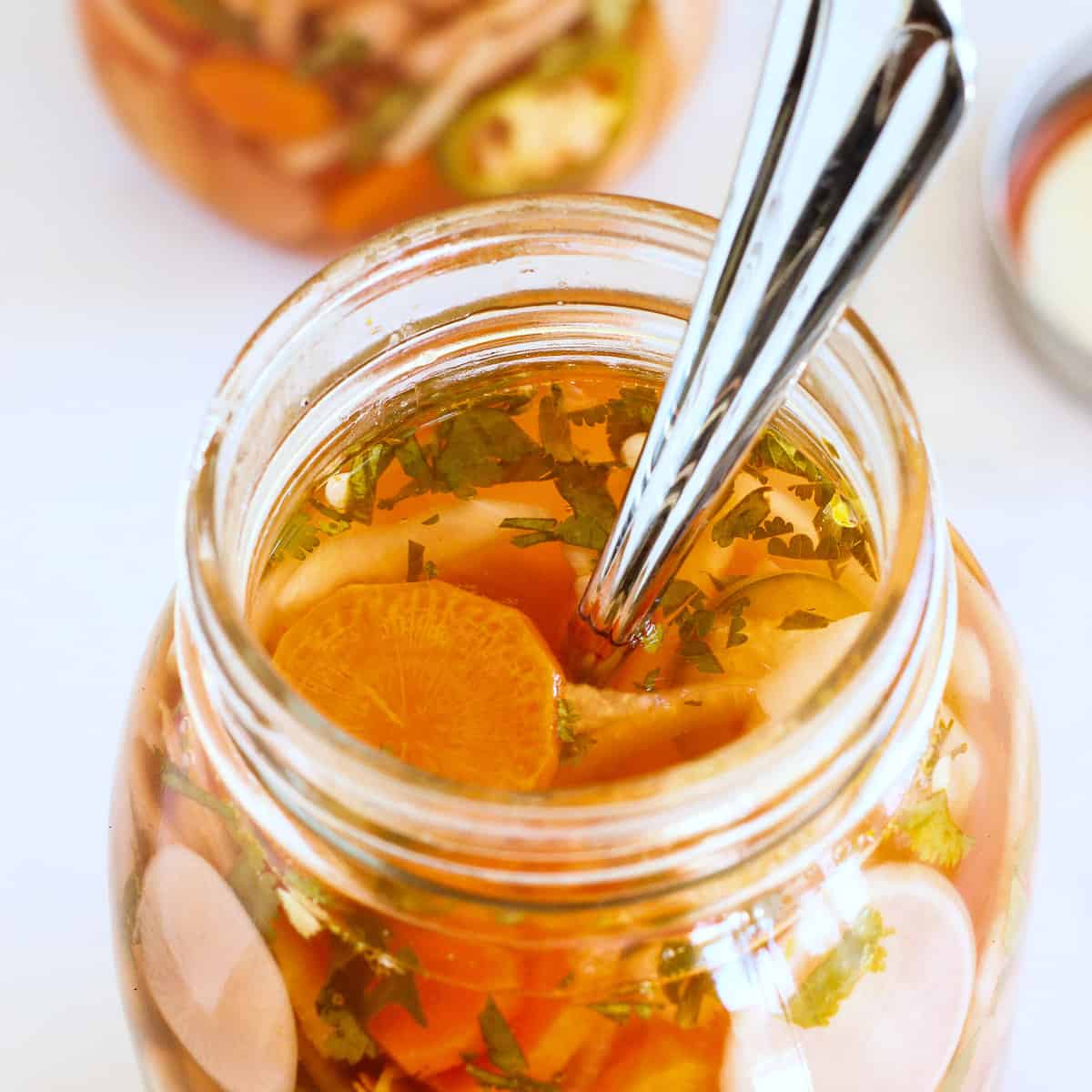 Looking into a jar of Mexican pickled vegetables. A spoon is in the jar.