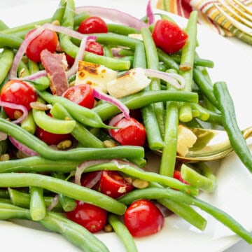 Cold green bean salad on a white plate.