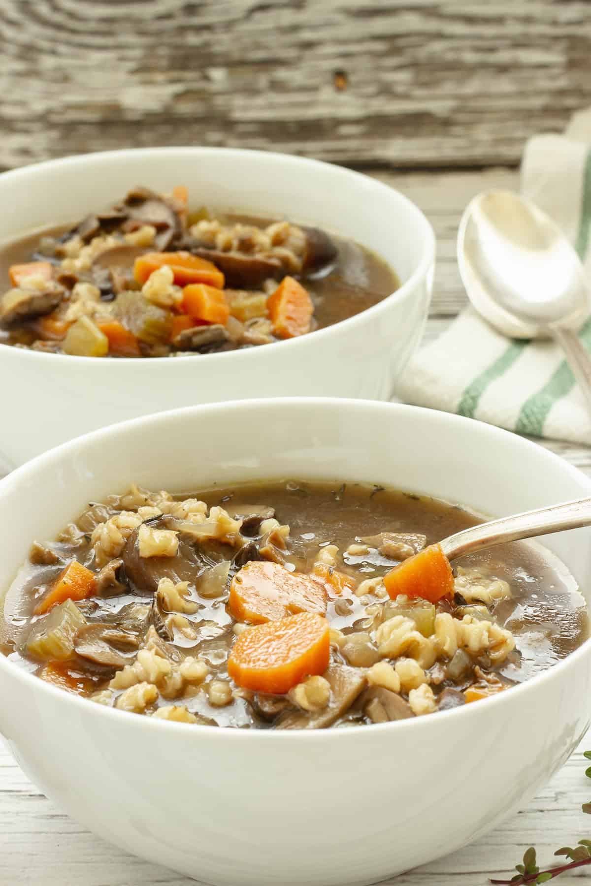 Two white bowls with mushroom barley soup.