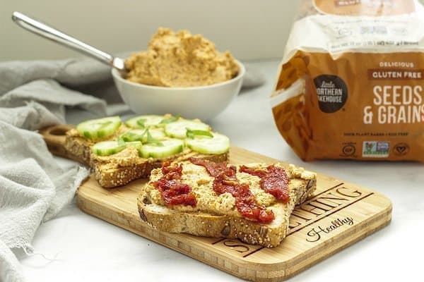 vegan almond cheese spread on toast and topped with cucumbers and sun dried tomatoes
