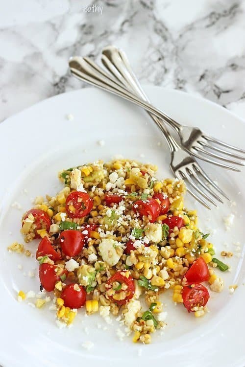 An overhead shot of a white plate of summer freekeh salad with corn and tomatoes.