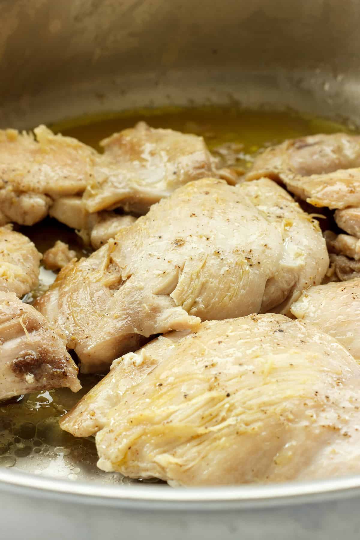 Chicken pieces browning in saute pan.