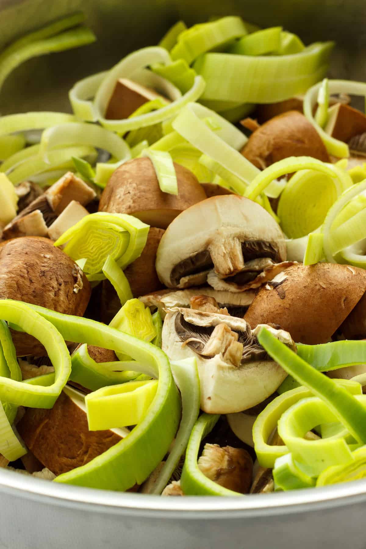 Sliced leeks and mushrooms cooking in a saute pan.