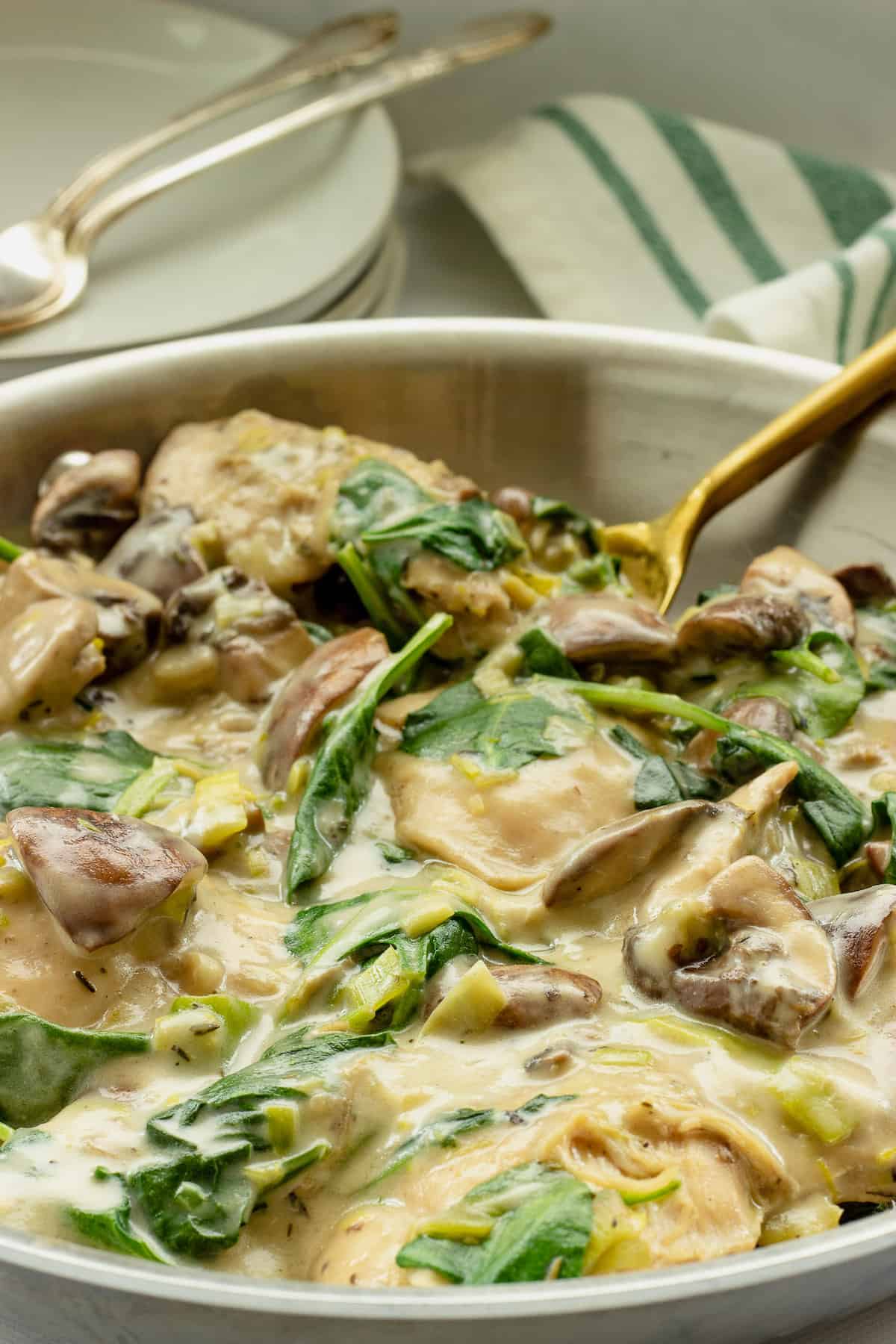 A close up shot of a skillet with creamy chicken with spinach and mushrooms