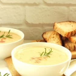 Creamy white bean fennel soup in a white bowl garnished with fresh rosemary