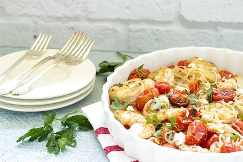A casserole dish with garlic shrimp and tomatoes over shirataki noodles.