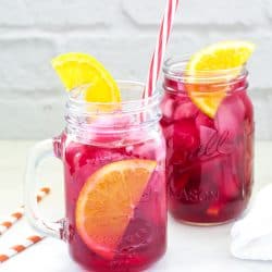 2 glasses of red hibiscus iced tea with orange slices