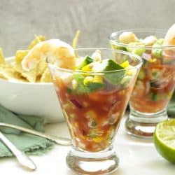 glass of Mexican Shrimp Cocktail with a white bowl of chips on a tray