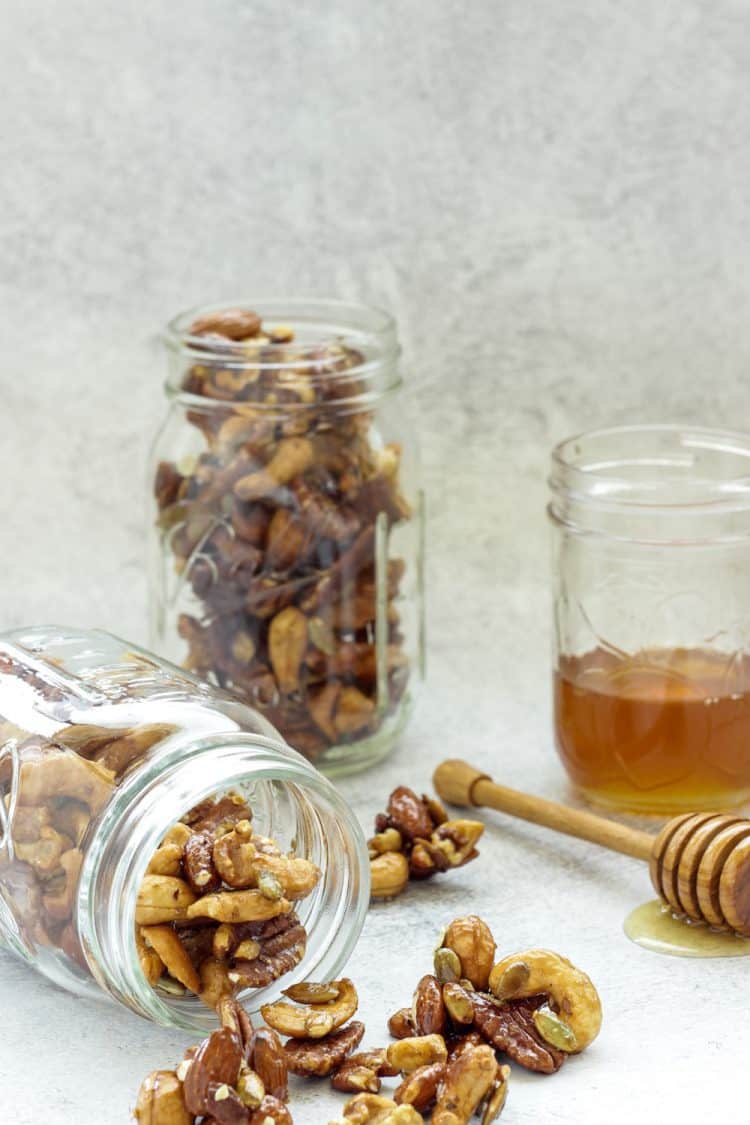 2 jars of mixed nuts with a jar of honey in the background