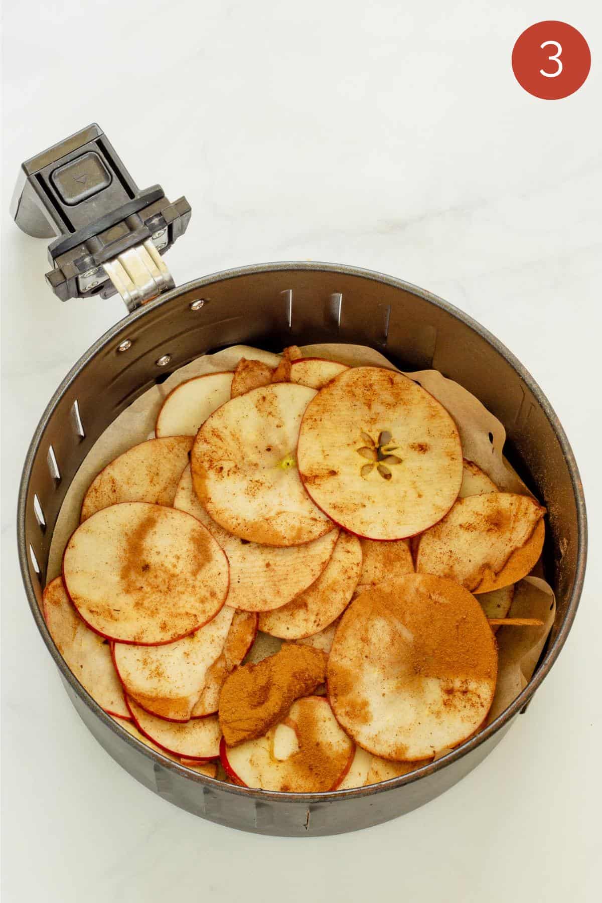 An air fryer basket with seasoned apple chips 