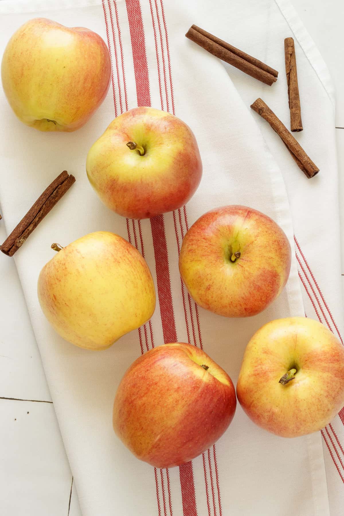 Apples and cinnamon sticks on a white and red striped napkin