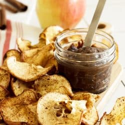 apple chips with a jar of chocolate dip and an apple in the background