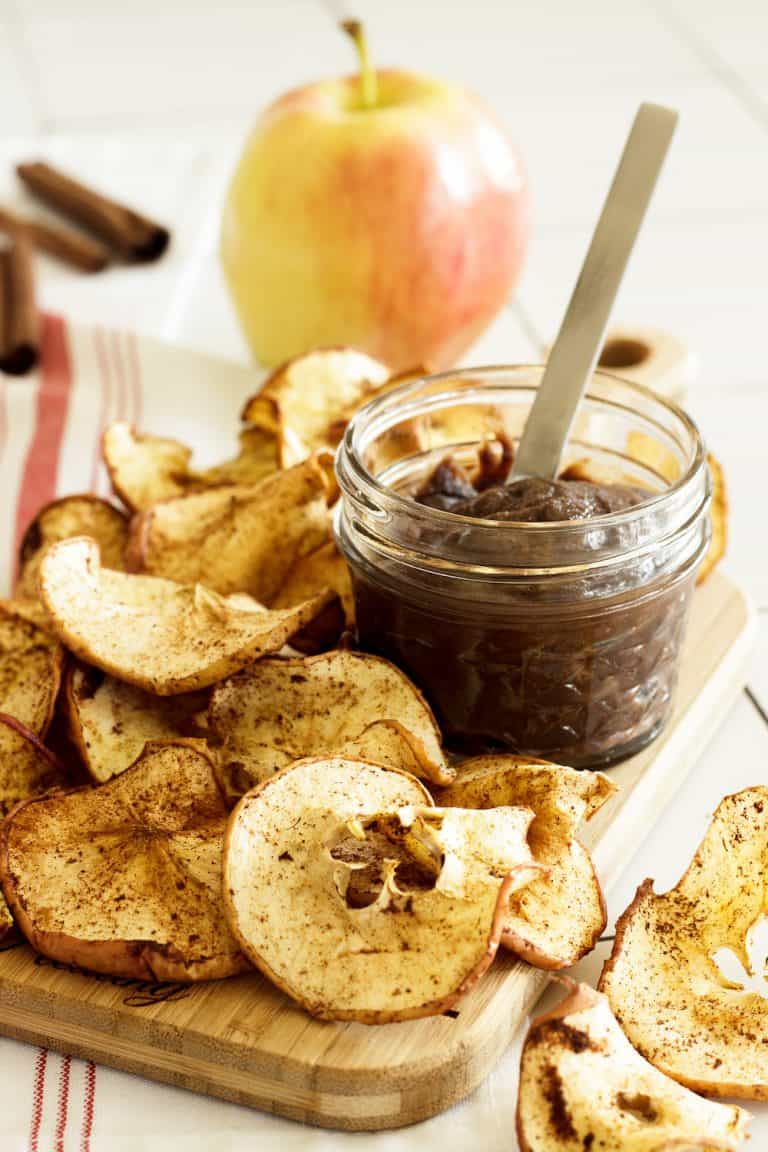 apple chips with a jar of chocolate dip and an apple in the background
