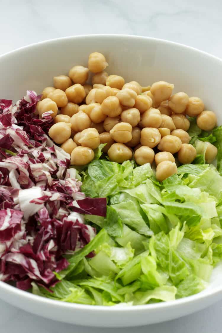 A white bowl with lettuce, radicchio, and chickpeas for a chopped Mediterranean salad.