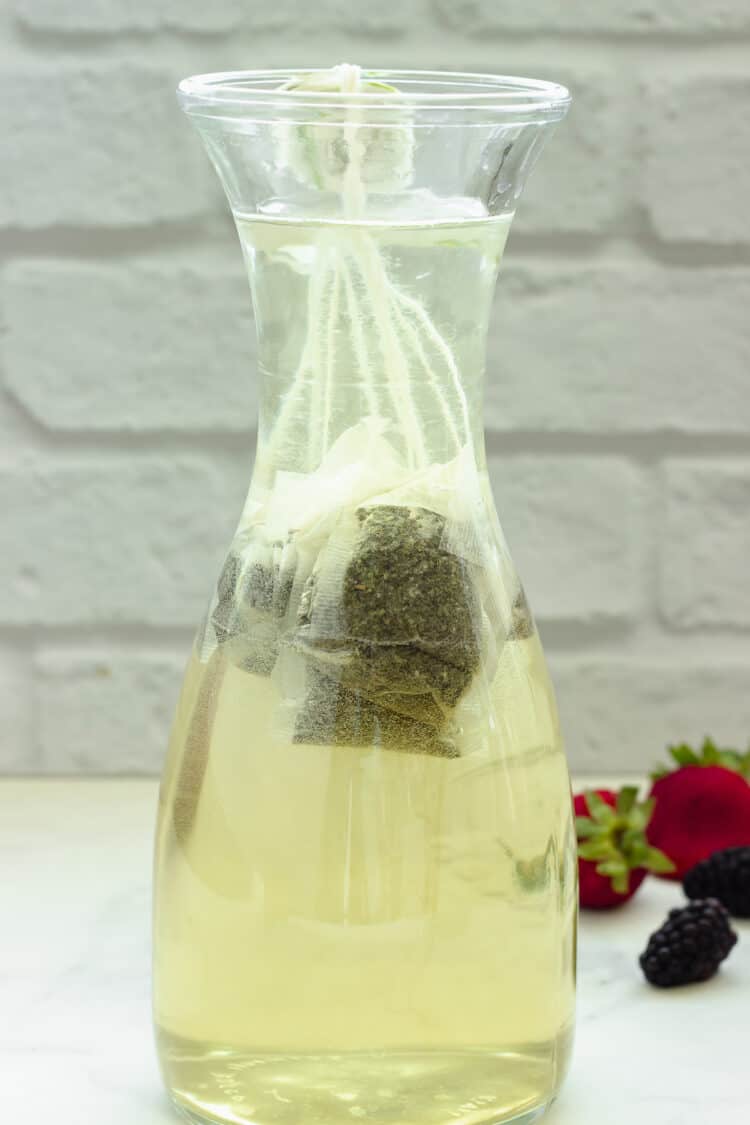 A carafe of water with green tea bags, cold brewed for about 5 minutes. Light green in color.