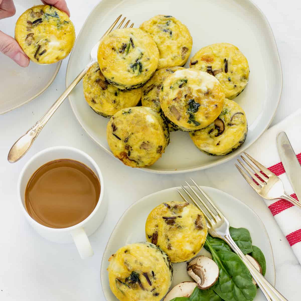 An overhead shot of a platter of egg muffin cups with a cup of coffee and a plate of 2 egg bites.