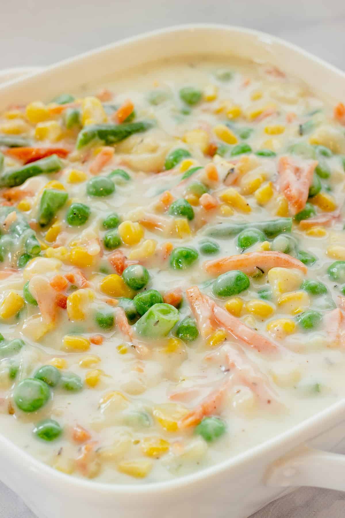 A casserole dish of mixed vegetables covered with Mornay sauce.
