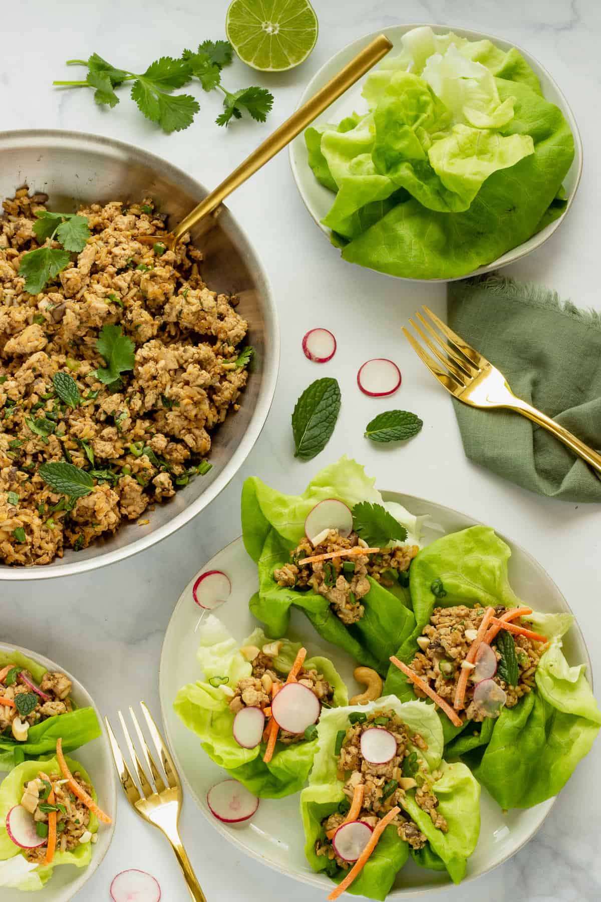 A pan of crumbled tofu filling with a white serving plate of assembled tofu lettuce wraps.