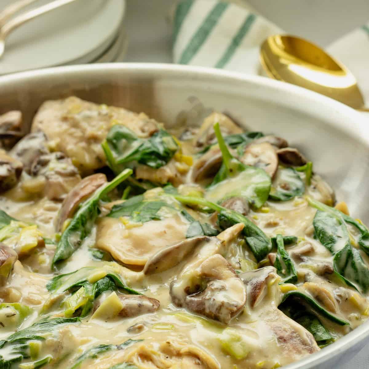 A pan of creamy chicken with spinach and mushrooms