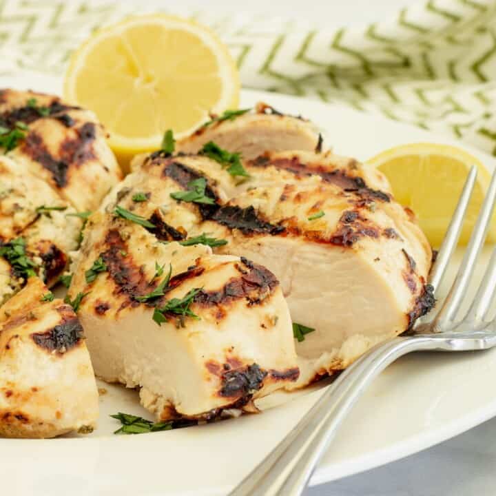 A plate with slices of Greek yogurt marinated chicken and a fork.