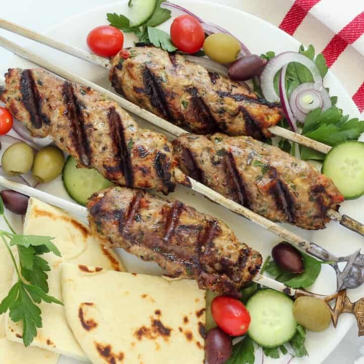 A platter of grilled chicken kofta skewers with pita bread.