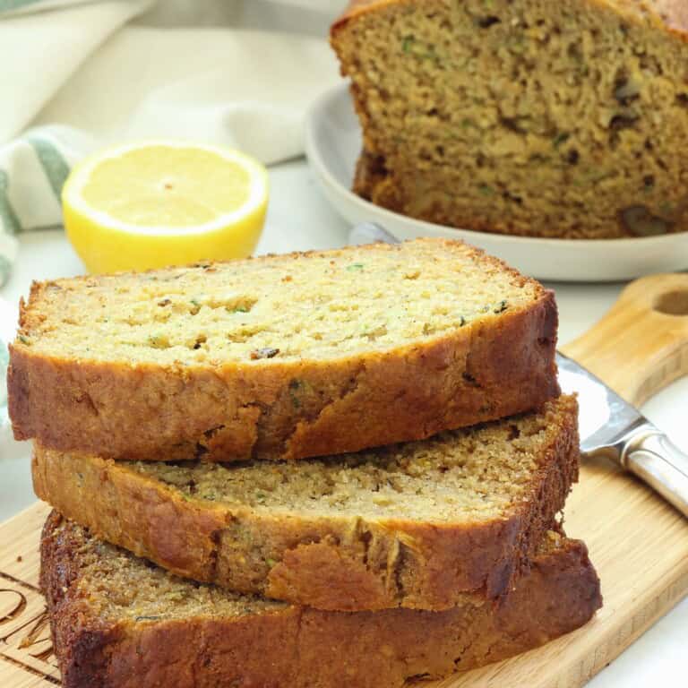 A stack of lemon zucchini bread slices on a wood board.